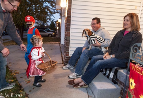 kids and dad visit with 2 people and dog seated on porch